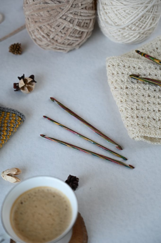 Beautiful wooden crochet hooks surrounded by yarn and a crocheted scarf.